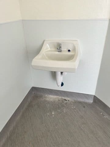 Wall-mounted sink in a clean, minimalist bathroom setting with tiled flooring.