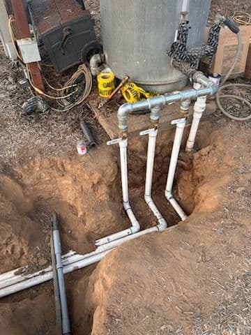 Piping system underground with connections to a water tank and surrounding equipment.