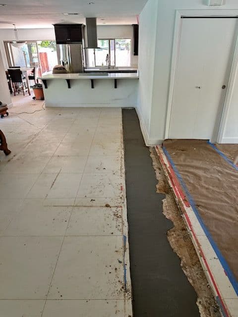 Home renovation in progress with flooring being laid in an open-concept living space.