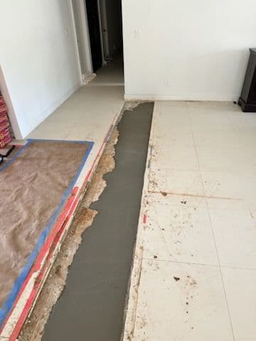 Freshly poured concrete leveling a floor with exposed subfloor in a renovation project.