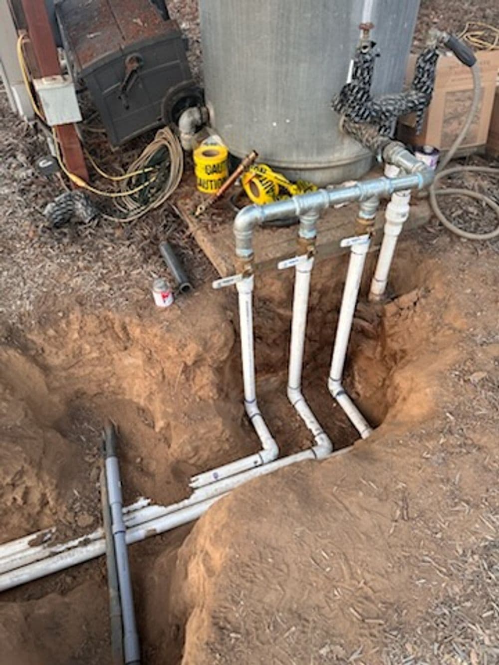 Underground piping system connected to a water heater in a construction site.